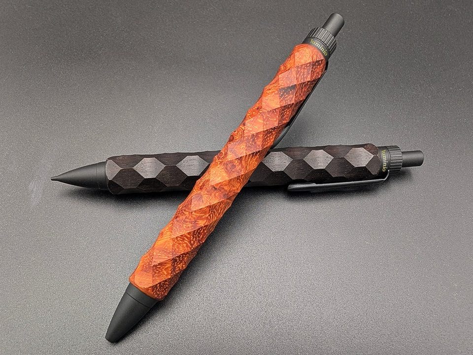 Two faceted wooden pens, one in red burl wood and one in dark ebony